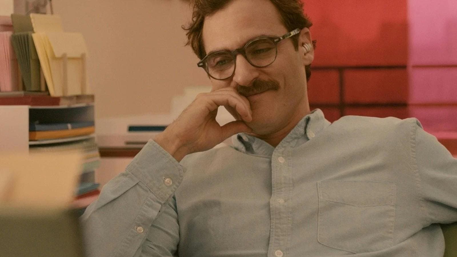 Man with moustache and glasses looking content smiling and looking down