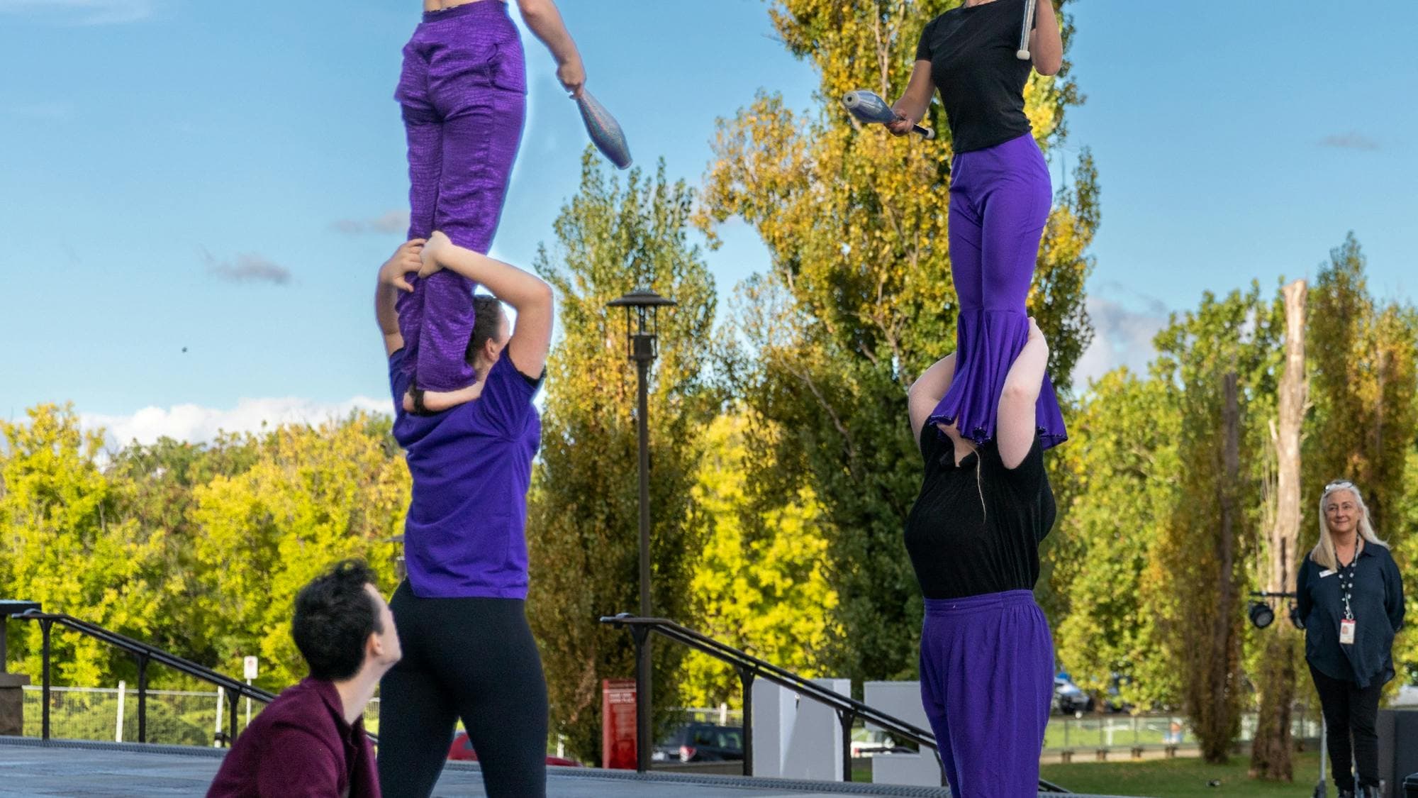 Warehouse Circus artists juggle to each other while balanced on shoulders